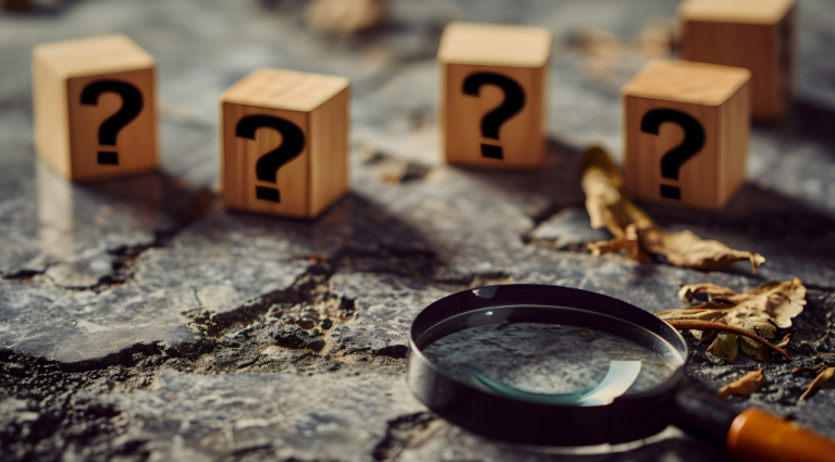 question marks on wooden cubes with magnify glass